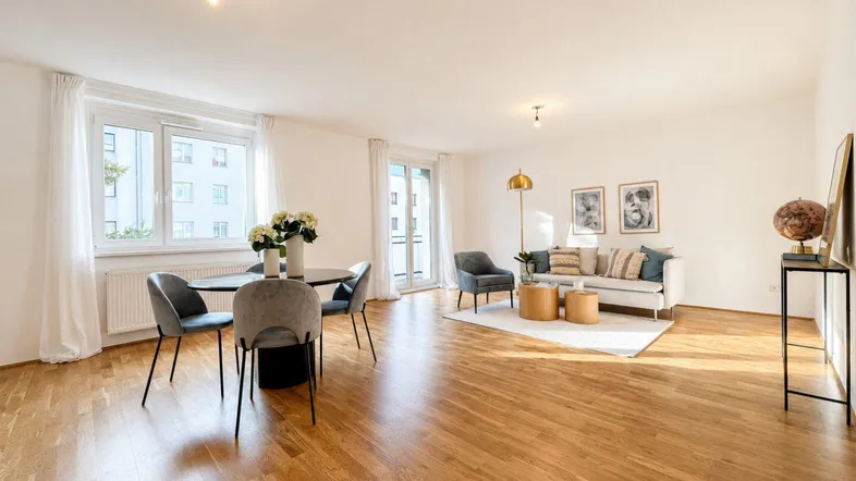 Helles und geräumiges Wohn-Esszimmer mit Parkettboden, modernen Möbeln und Zugang zum Balkon.