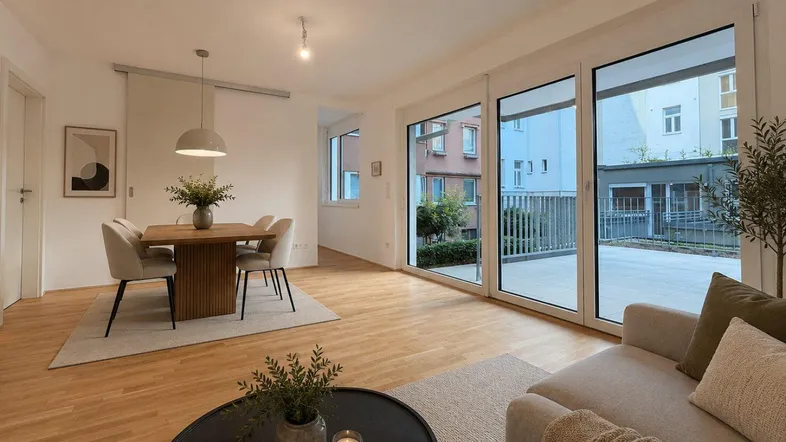 Helles, modern eingerichtetes Wohn-Esszimmer mit Holzboden und Zugang zur großen Terrasse.