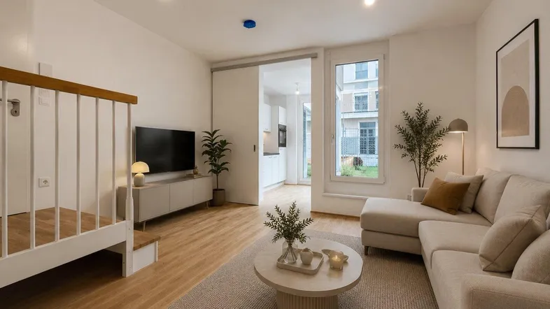 Modernes, helles Wohnzimmer mit Holzboden, beigem Sofa und Blick in die Küche sowie zum Garten.