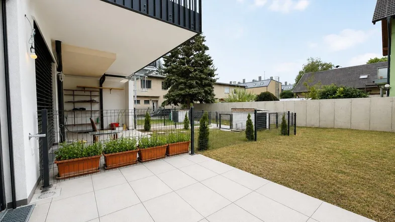 Grosse geflieste Terrasse mit Blumenkästen und angrenzendem Rasenbereich und Balkon.