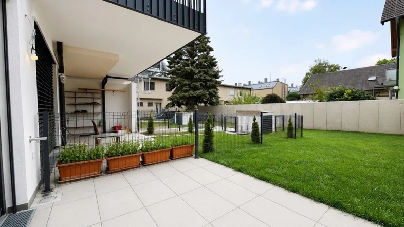 Geflieste Terrasse mit angrenzendem Rasenbereich und Blick auf die Umgebung.