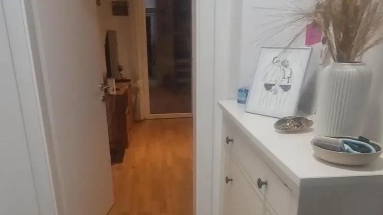 Heller Flur mit gemusterten Fliesen und einem Schuhschrank, der zu einem weiteren Raum führt.