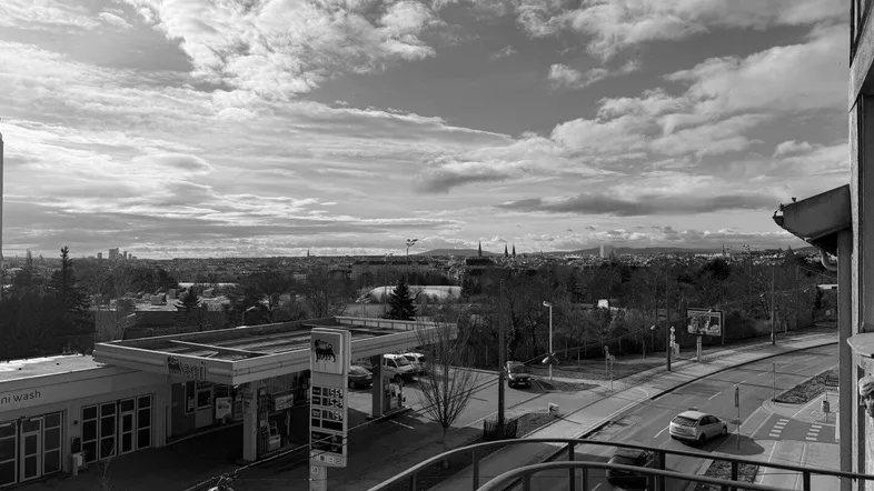 Blick vom Balkon auf eine Tankstelle, eine Straße und die Stadt in der Ferne.