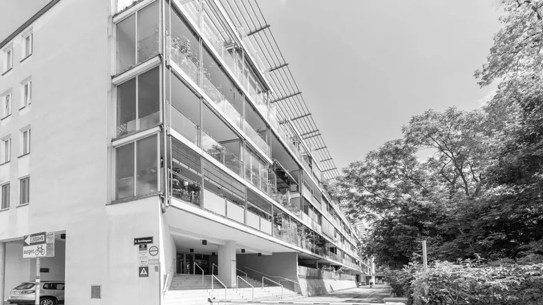 Modernes Mehrfamilienhaus mit großen Glasfronten und Balkonen in Schwarz-Weiß-Aufnahme.
