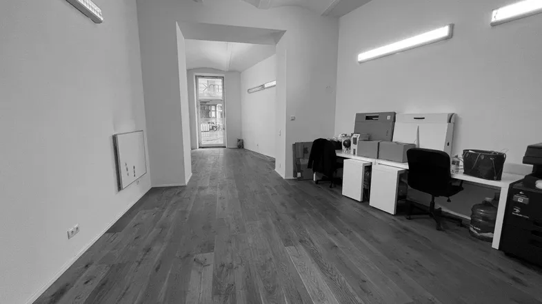Geräumiger, heller Büroraum mit Holzboden und modernen Leuchten, bereit zur Nutzung.