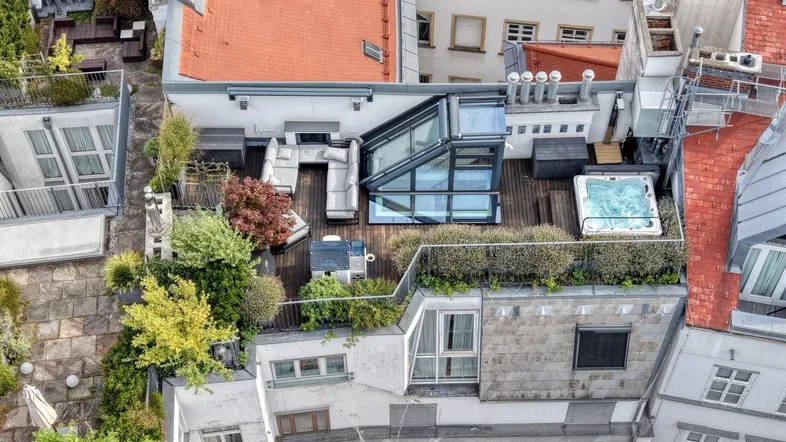 Luftaufnahme einer luxuriösen Dachterrasse mit Whirlpool, Sitzbereich und üppiger Bepflanzung.
