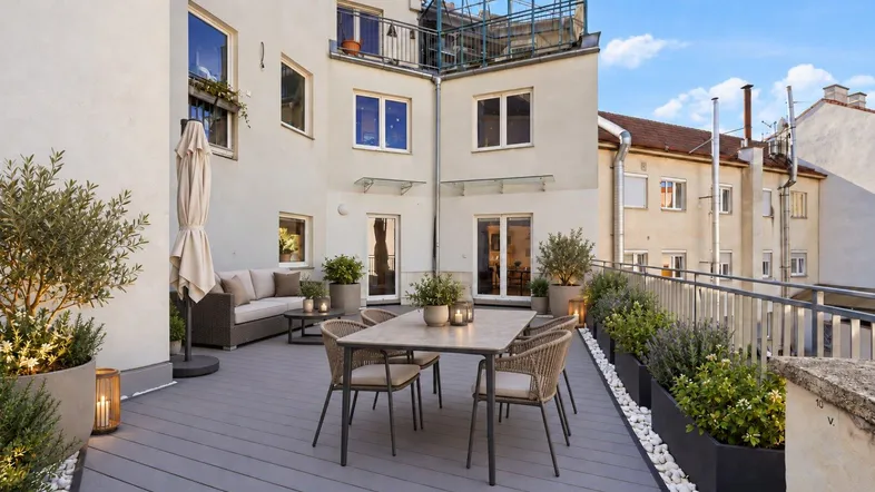 Großzügige Terrasse mit modernen Gartenmöbeln, Pflanzen und Blick auf die umliegenden Gebäude.
