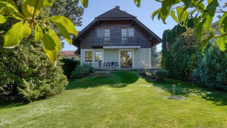 Charmantes Einfamilienhaus mit großem, gepflegtem Garten und Balkon, umgeben von viel Grün.