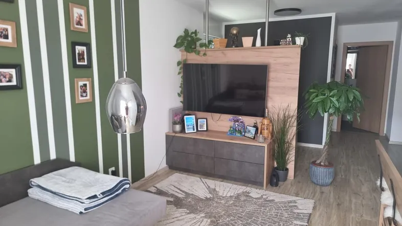 Modernes Wohnzimmer mit grüner Streifenwand, TV-Möbel und hellem Laminatboden.