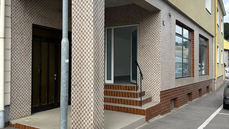 Gebäudeeingang mit gefliester Veranda und gelber Fassade an einer Straße gelegen, mit einem Laternenpfahl davor.