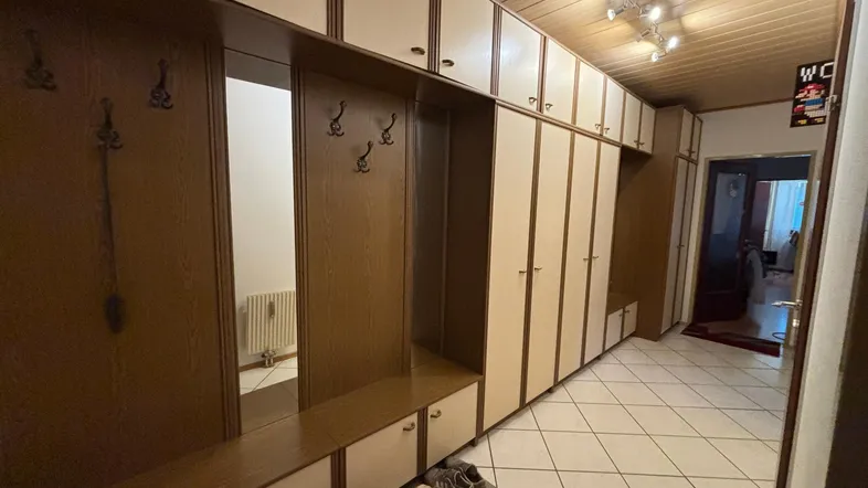 Geräumiger Flur mit umfangreichen Einbauschränken, Garderobe und hellem Fliesenboden.