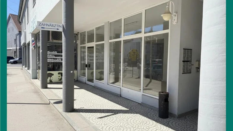 Helle Geschäftsfassade mit großen Schaufenstern und modernem Design, gut beleuchtet von der Sonne.