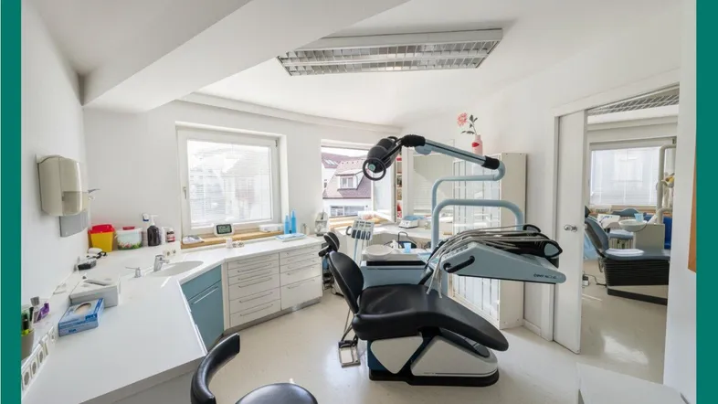 Heller Behandlungsraum einer Zahnarztpraxis mit moderner Ausstattung und großem Fenster.