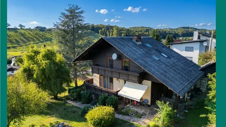 Charmantes Landhaus mit traditioneller Holzfassade und weitläufigem Grundstück in grüner Hügellandschaft.