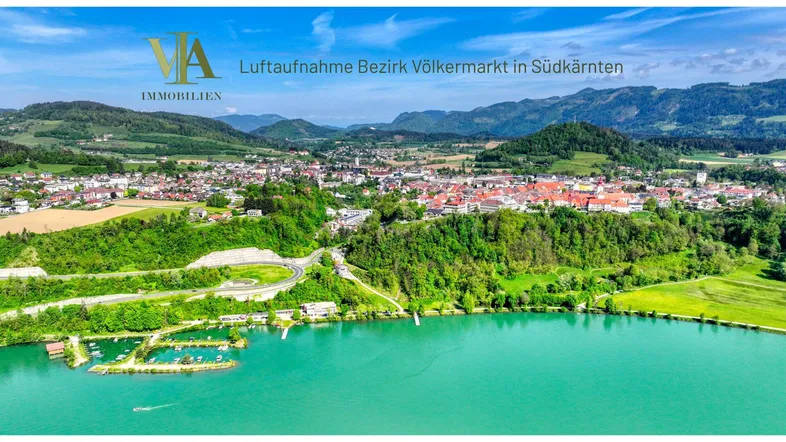 Luftaufnahme des Bezirks Völkermarkt in Südkärnten mit See, Stadt und umliegenden Bergen.