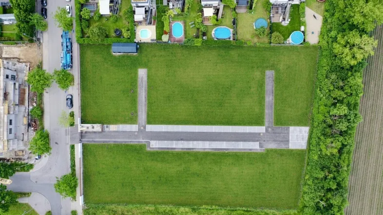 Luftaufnahme von Baugrundstücken mit angrenzenden modernen Häusern und Gärten mit Pools.