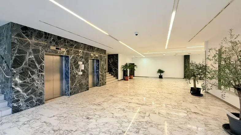 Geräumige und helle Lobby mit luxuriösem Marmorboden und Wänden, sowie zwei modernen Aufzügen.