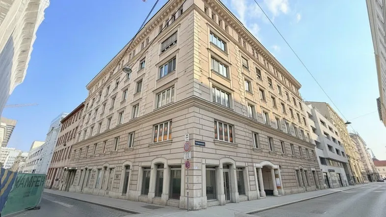Historisches Eckgebäude mit klassischer Fassade und vielen Fenstern an einer städtischen Kreuzung.