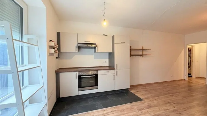 Moderne Einbauküche mit Geräten und Holzfußboden, offen zum Wohnbereich mit großem Fenster.