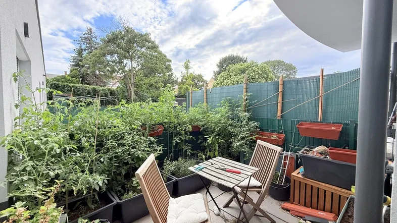 Gemütliche Terrasse mit vielen Pflanzen und einem kleinen Tisch für entspannte Stunden im Freien.