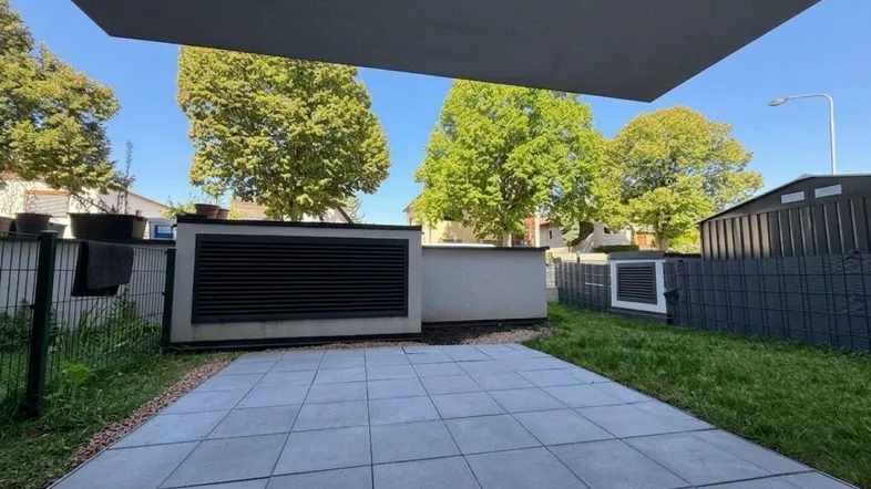Große gepflasterte Terrasse mit angrenzender Rasenfläche und Blick ins Grüne.