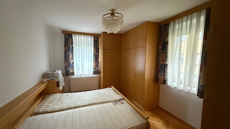 Helles Schlafzimmer mit Doppelbett, Einbauschränken und klassischem Parkettboden.