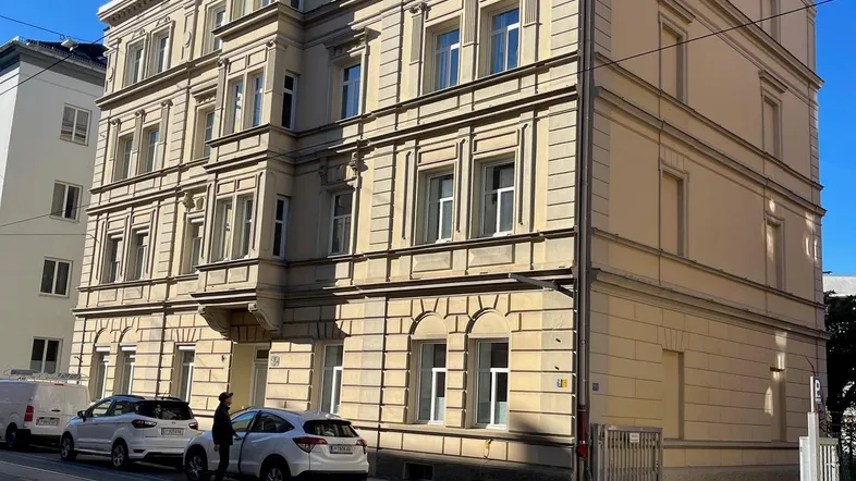 Klassisches Mehrfamilienhaus mit historischer Fassade und großen Fenstern an einer Stadtstraße.