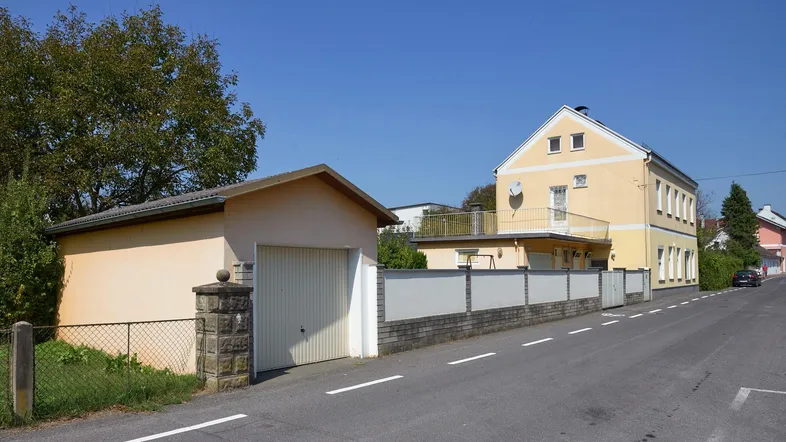 Gelbes Wohnhaus mit separater Garage und Zaun an einer ruhigen Straße gelegen.