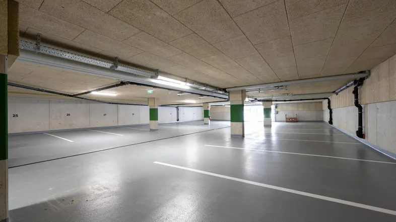Geräumige Tiefgarage mit markierten Stellplätzen, guter Beleuchtung und sichtbaren Installationen.