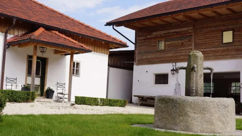 Ländliches Anwesen mit traditionellen Gebäuden, Innenhof und einem historischen Steinbrunnen.