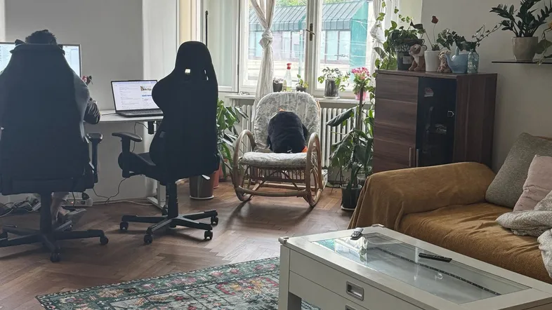 Helles Wohnzimmer mit Fischgrätparkett, einem Arbeitsbereich und gemütlicher Sitzecke am Fenster.