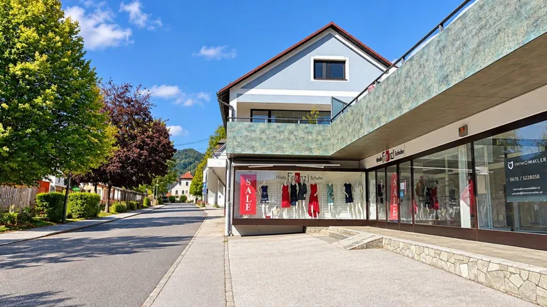Außenansicht eines Geschäftsgebäudes mit Schaufenstern und einer Rampe zum Eingangsbereich.