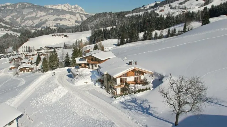 Großzügiges Anwesen in verschneiter Berglandschaft mit traditioneller Architektur und weitem Blick.
