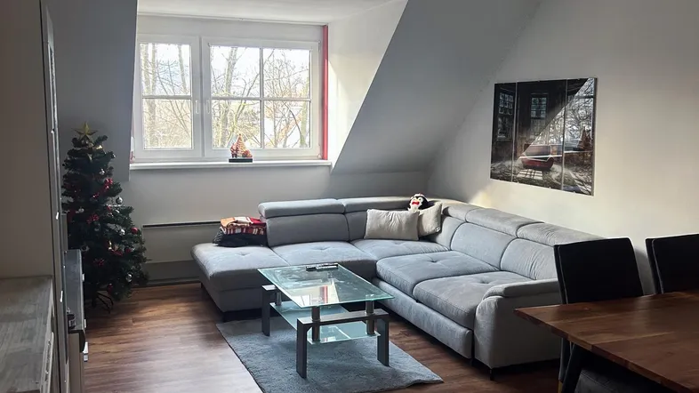 Gemütlicher Wohn-Essbereich mit Ecksofa, Couchtisch und Esstisch unter einer Dachschräge.