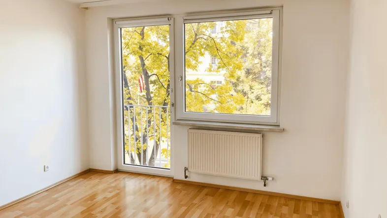 Helles Zimmer mit Parkettboden und Zugang zu einem französischen Balkon, ideal als Wohn- oder Schlafbereich.