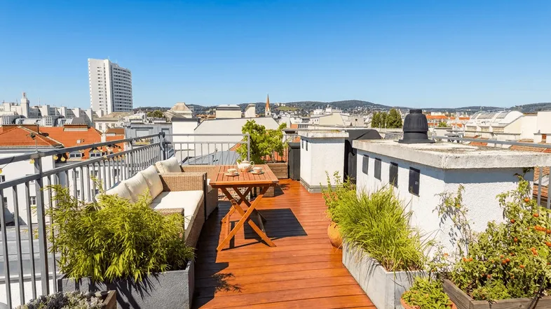 Weitläufige Dachterrasse mit Loungemöbeln, Pflanzen und einem beeindruckenden Panoramablick über die Stadt.