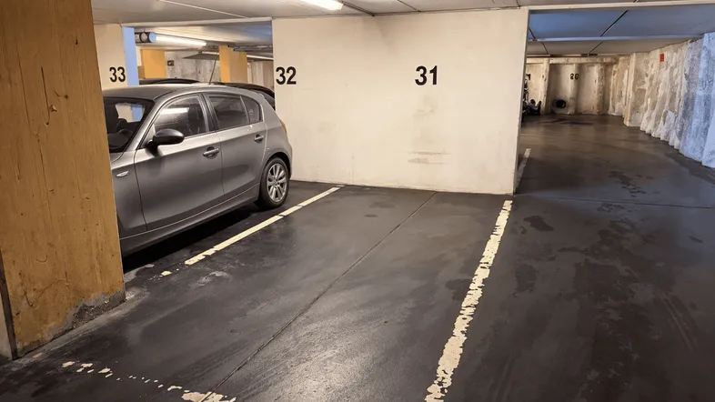 Tiefgarage mit nummerierten Stellplätzen und einem geparkten Auto, gut beleuchtet und sauber.