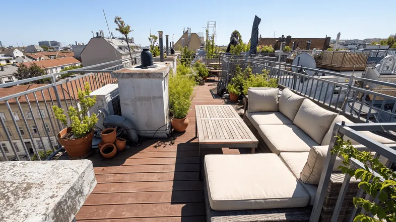 Geräumige Dachterrasse mit bequemen Loungemöbeln, Pflanzen und weitem Blick über die Stadt.