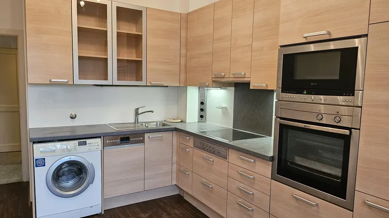 Moderne Einbauküche mit hellen Holzfronten, integrierten Geräten und einer Waschmaschine.