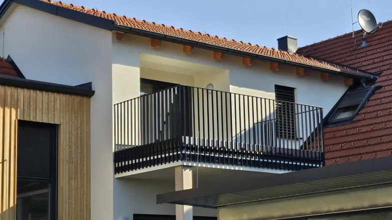 Moderner Balkon mit schwarzem Geländer an einem Wohngebäude mit Holzverkleidung.