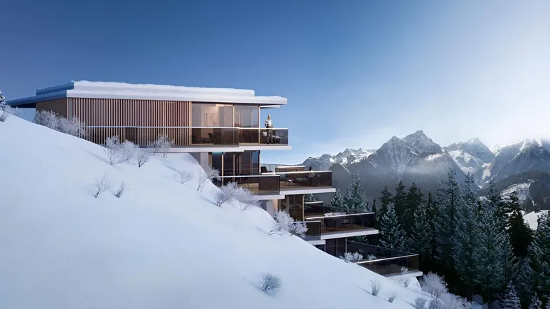 Moderne Architektur in den Bergen mit großen Glasfronten und Terrassen, umgeben von Schnee.
