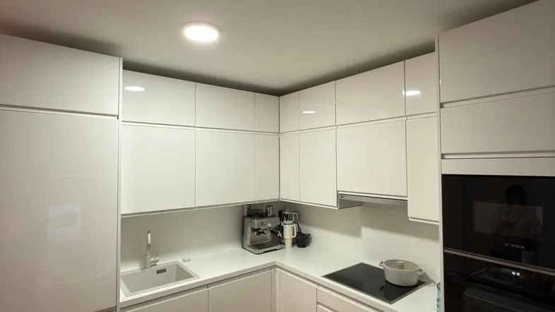 Moderne Einbauküche mit weißen Hochglanzfronten, Induktionskochfeld und integriertem Backofen.