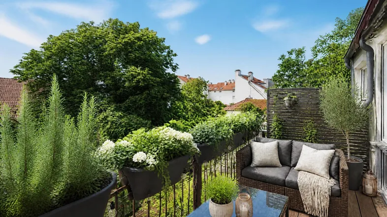 Gemütlicher Balkon mit Holzboden, Sitzgelegenheiten und üppiger Bepflanzung mit Blick ins Grüne.