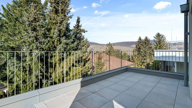 Große, geflieste Terrasse mit Metallgeländer und weitem Blick ins Grüne und auf die Landschaft.