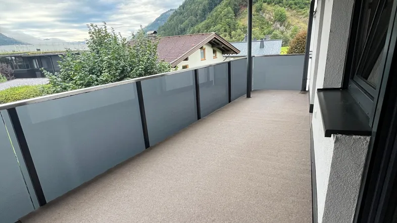 Geräumiger Balkon mit Bergblick, modernem Glasgeländer und Holzdach.