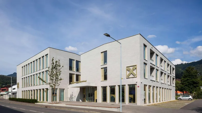 Modernes Gebäude mit heller Fassade und großen Fenstern an einer Straße gelegen.