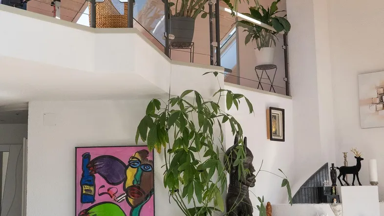Heller Wohnbereich mit Kunstwerken, Kamin und Blick auf die obere Etage.