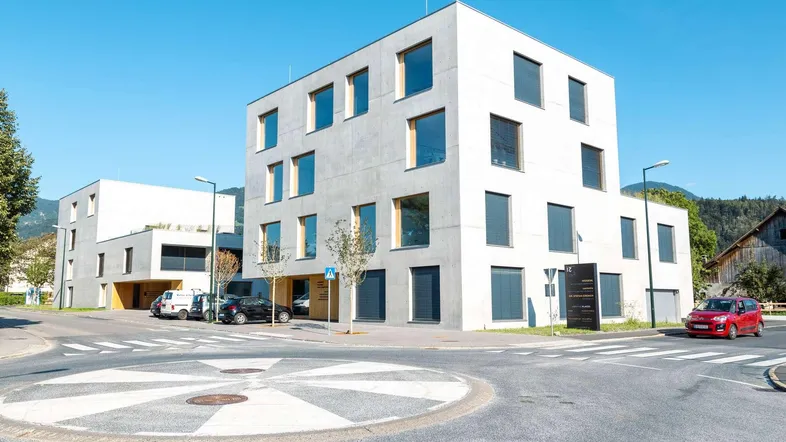 Modernes Bürogebäude mit klarer Architektur und großen Fenstern an einer Straßenecke.