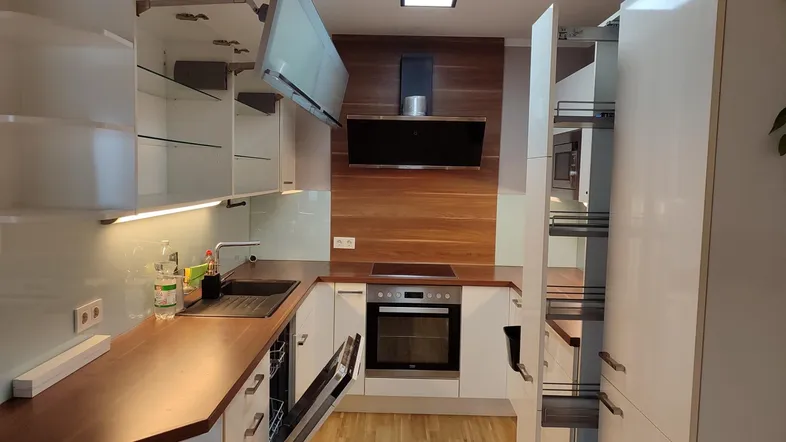 Moderne Küche mit weißen Schränken, Holz-Arbeitsplatten und integrierten Geräten.