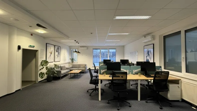 Modern eingerichtetes Großraumbüro mit mehreren Arbeitsplätzen und einem gemütlichen Lounge-Bereich.